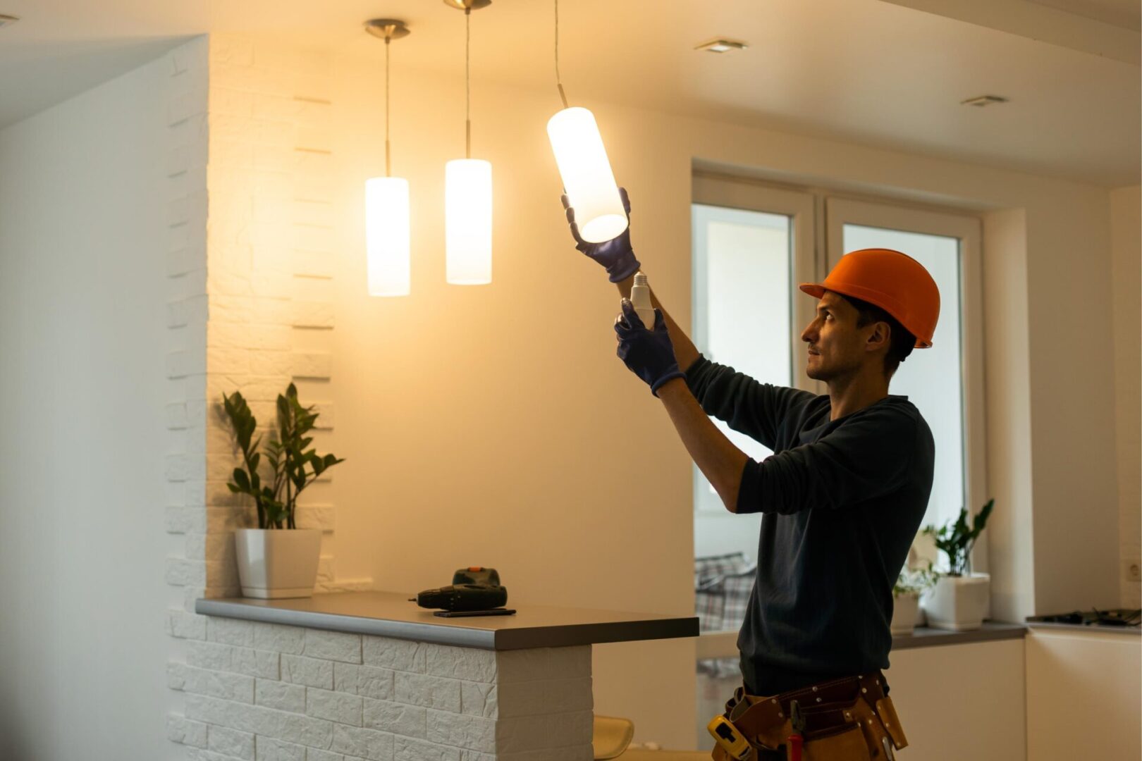 Worker installing light fixture in room.